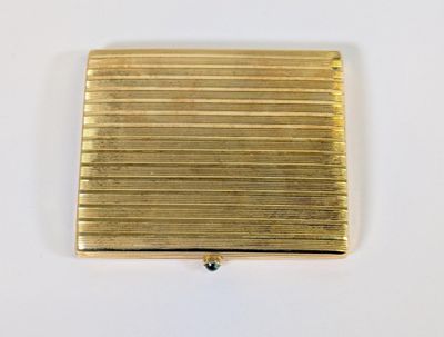 une photo d'un étui à cigarettes en or posé sur une table blanche