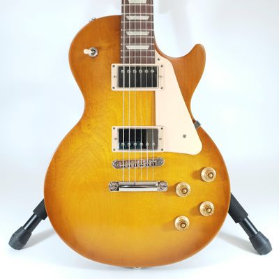 an electric guitar sitting on top of a stand on a white surface