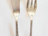 two forks and a spoon on a white surface