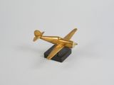 figurine d'avion dorée sur socle noir, sur fond blanc