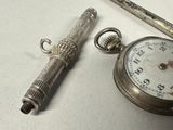 a silver pocket watch and a pen on a table