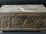 an old wooden box with carvings on it sitting on a black surface
