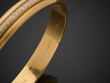 a close up of a gold bracelet with diamonds on a black background