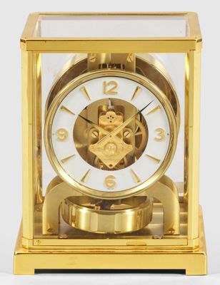 une horloge en or posée sur une surface blanche