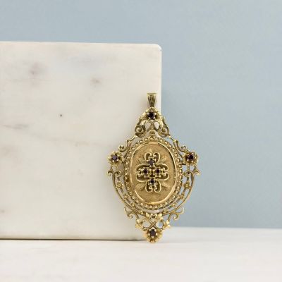 un gros plan d'un pendentif en or posé sur un bloc de marbre blanc