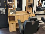 une photo d'un salon de coiffure avec des fauteuils et un miroir