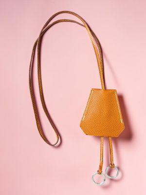 an orange leather purse with a metal hook on a pink background