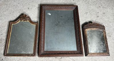 trois miroirs anciens sont posés par terre, les uns à côté des autres