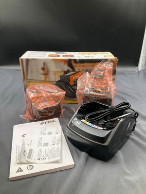 a box of oranges sitting on a bed next to a charger