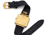 a close up of a watch on a white surface with a gold buckle