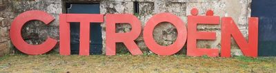 une enseigne rouge portant l'inscription « Citroën » devant un immeuble