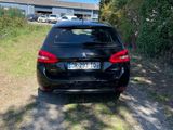 a black car parked on the side of a dirt road
