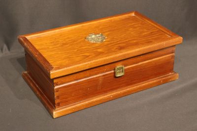 an old wooden box sitting on a grey cloth covered surface