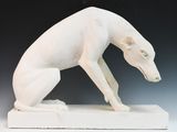 une sculpture blanche représentant un chien assis sur un socle blanc