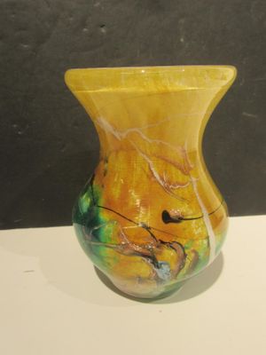 a yellow vase sitting on a white table with a black background