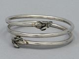 three silver bang bracelets with fish charms on them on a white surface