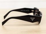 black prada sunglasses on a wooden table with a white wall in the background