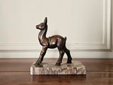 une statue en bronze représentant un cerf, posée sur un socle en marbre