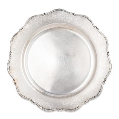 une assiette ancienne en argent au bord festonné sur fond blanc