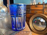 a blue glass cup sitting on top of a wooden table