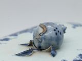 a close up of a blue and white plate with a fish on it
