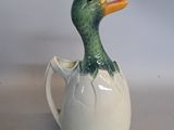 a ceramic duck that is sitting inside of a cup