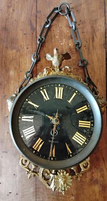 une horloge accrochée au mur, entourée d'une chaîne