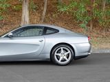 silver sports car parked on the side of the road in front of a wooded area