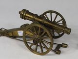 an antique brass cannon on a chain next to a key