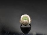 a close up of a silver ring with a green stone in it