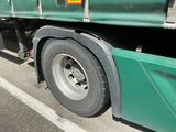 un grand camion vert garé sur le bord de la route