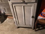 a small cabinet and a chair in the corner of a room