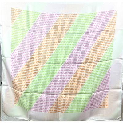 une chaise blanche recouverte d'une couverture rayée verte et rose
