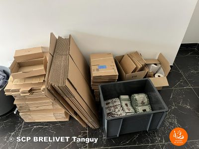 a pile of boxes and boxes sitting on the floor next to a trash can