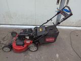 a picture of a lawn mower parked outside of a garage