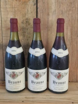three bottles of wine are lined up on a wooden shelf