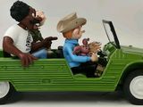 two figurines of a man and a woman in a green jeep