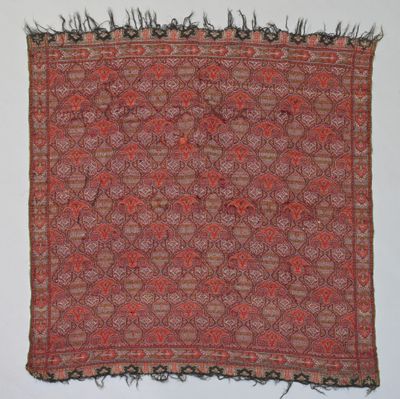 un tapis orange et marron à franges accroché au mur