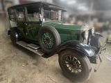 an old green car that is parked in a garage