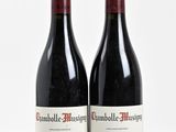 two bottles of red wine sitting next to each other on a white surface