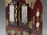 une petite boîte rouge et dorée sur laquelle est représentée une horloge