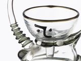 a glass jar with a metal handle and a glass bowl on top of it