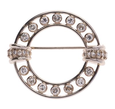 un gros plan d'une broche circulaire sertie de diamants sur fond blanc