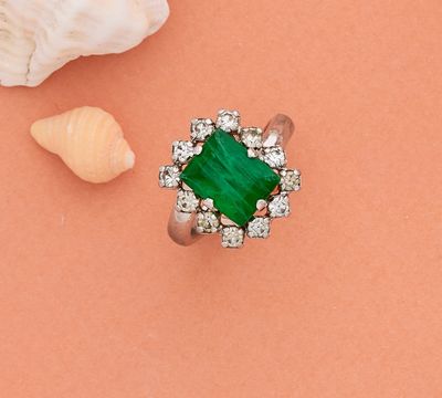 gros plan d'une bague avec une pierre verte entourée de diamants