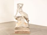 statue d'une femme assise sur un rocher dans une pièce blanche
