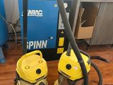 deux aspirateurs jaunes posés sur un parquet, à côté d'une machine bleue