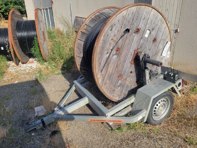 une remorque équipée d'un dévidoir, garée devant un immeuble