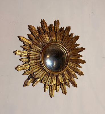 un motif doré en forme de rayons de soleil accroché au mur au-dessus d'un miroir