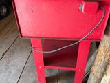 a red cooler sitting on a wooden floor next to a pile of wood