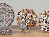 trois assiettes et un vase posés sur une table, avec un mur en arrière-plan